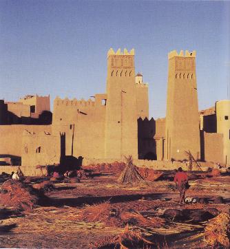 Refurbished earthen city walls in Morocco, with crenellated towers along the rampart.